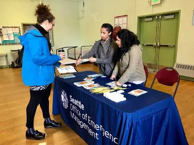 Two office of emergency management women hand out materials to a Beacon Hill resident
